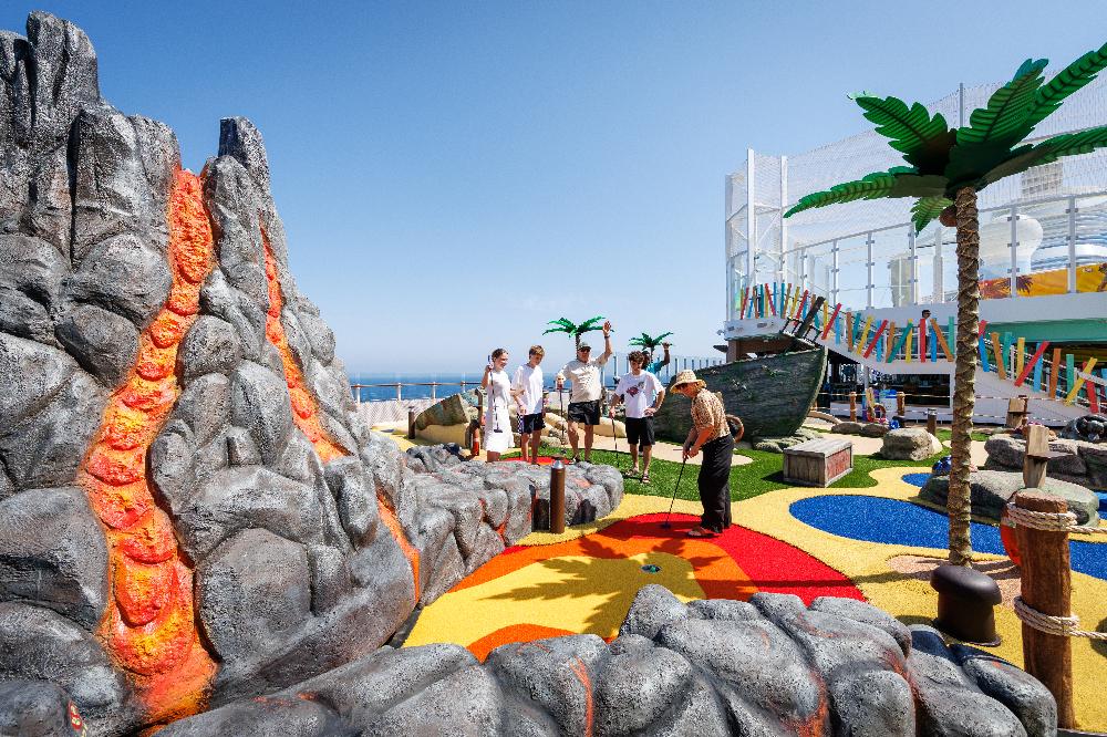 Family playing mini golf beside an erupting volcano feature on deck