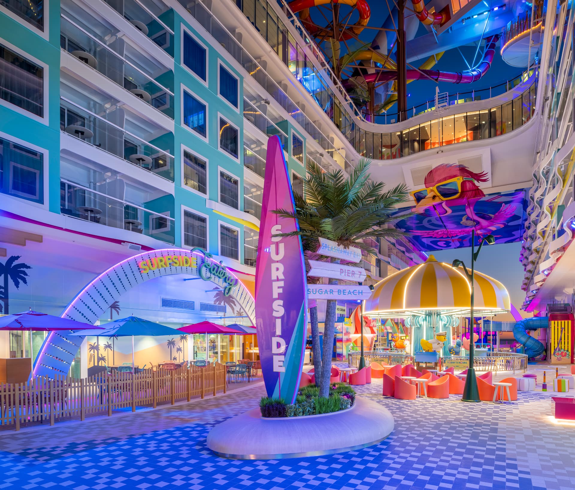 Vibrant Surfside neighbourhood at night with a giant illuminated surfboard sign, carousel and colourful seating