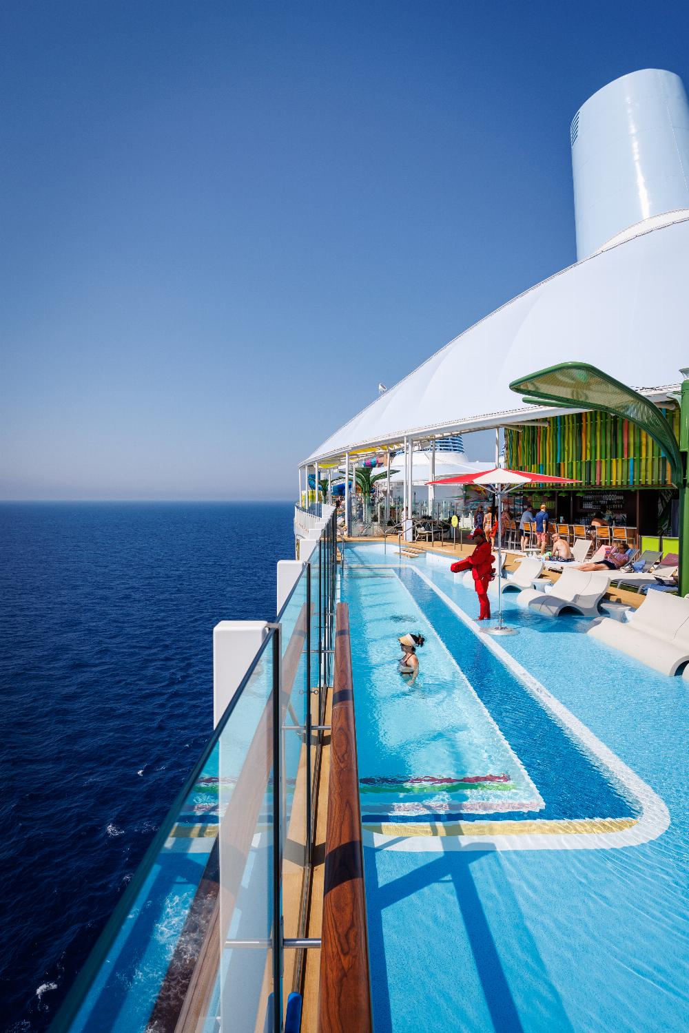 Long lap pool alongside sun loungers and the open ocean on Legend of the Seas