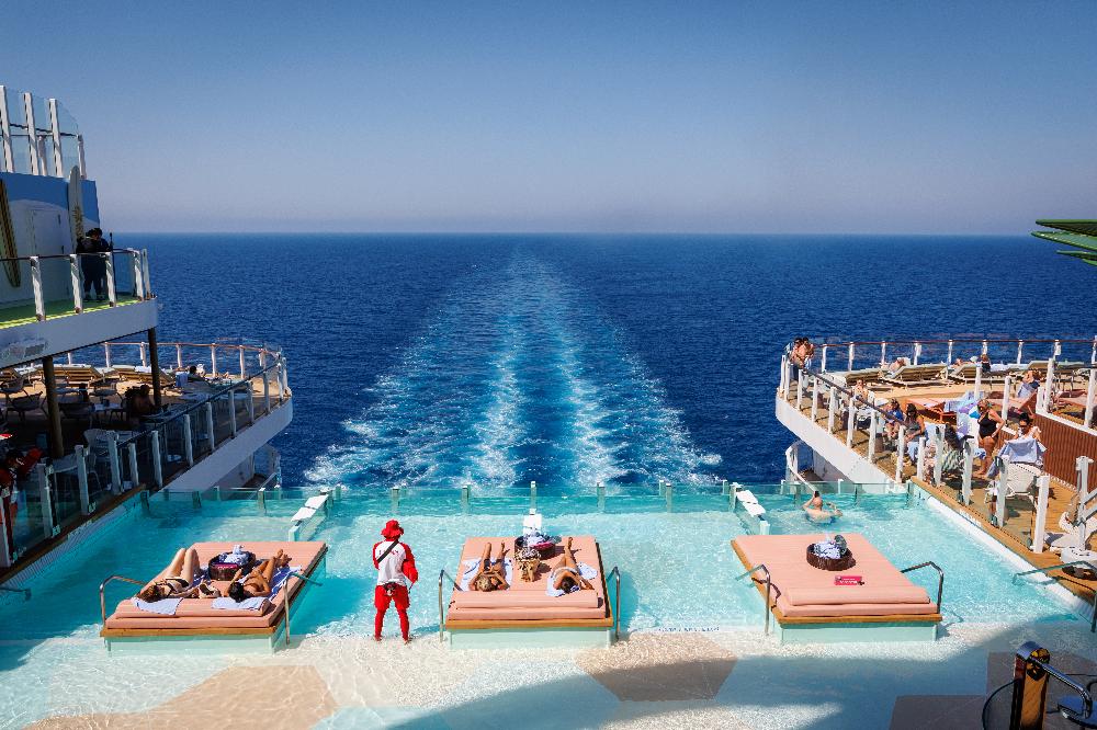 Guests on in-water loungers in the aft infinity pool overlooking the ship's wake